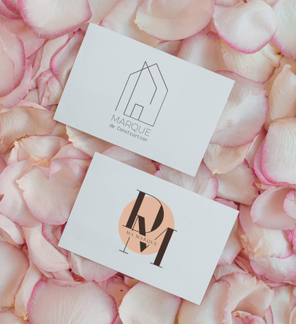 Deux cartes de visite avec des logos sur un lit de pétales de roses